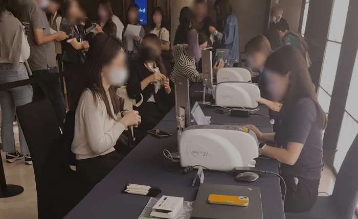 카드 프린터가 놓인 긴 테이블에서 참가자가 카드를 받는 모습